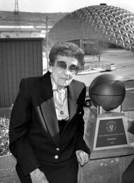Bertha Teague poses with the 1990 championship trophy that bears her name. Behind her is the Kerr Activities Center where the tournament is played every December.